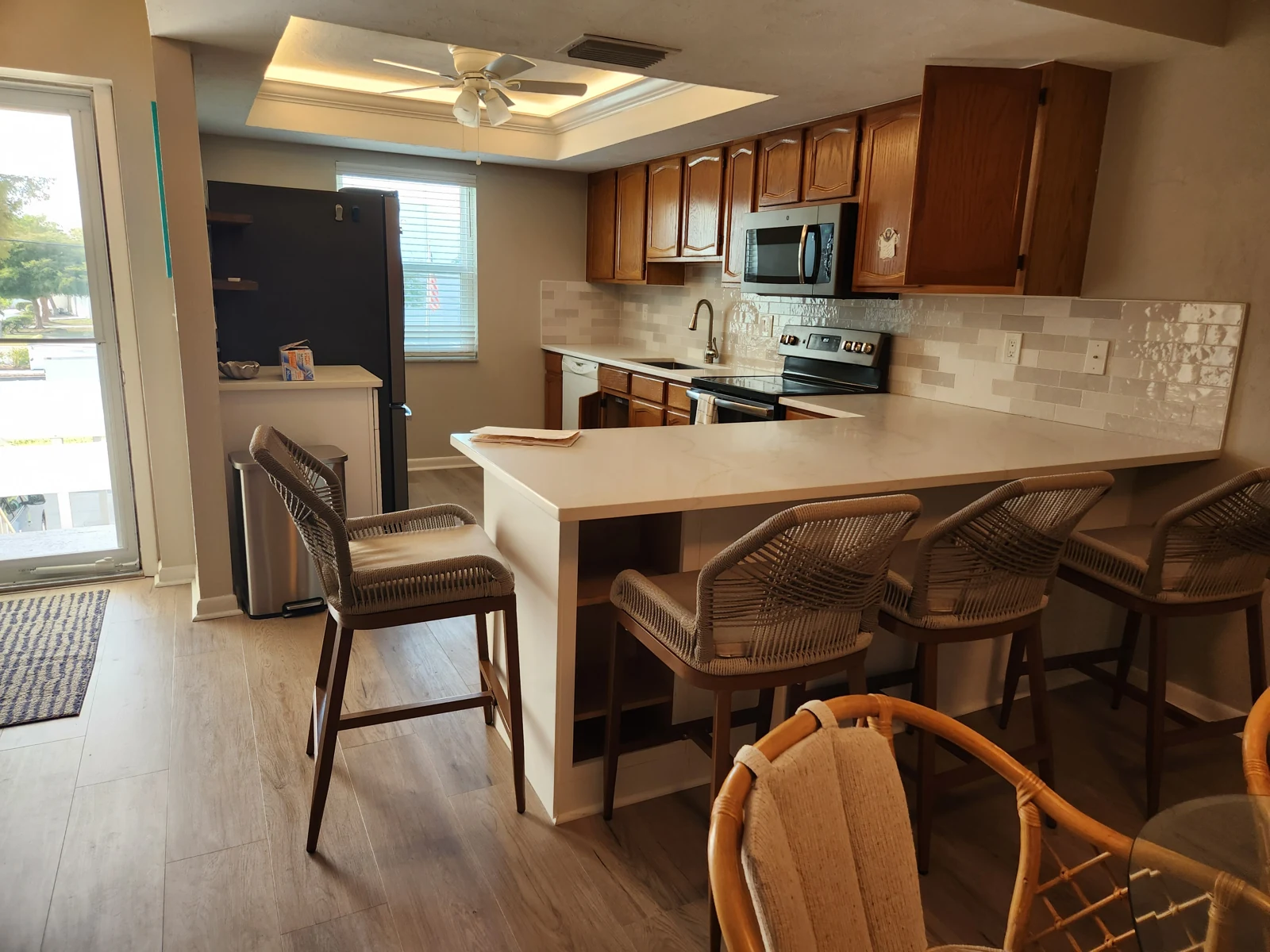 Kitchen with original wood cabinet fronts, a peninsula seating counter and tile backsplash, before refacing