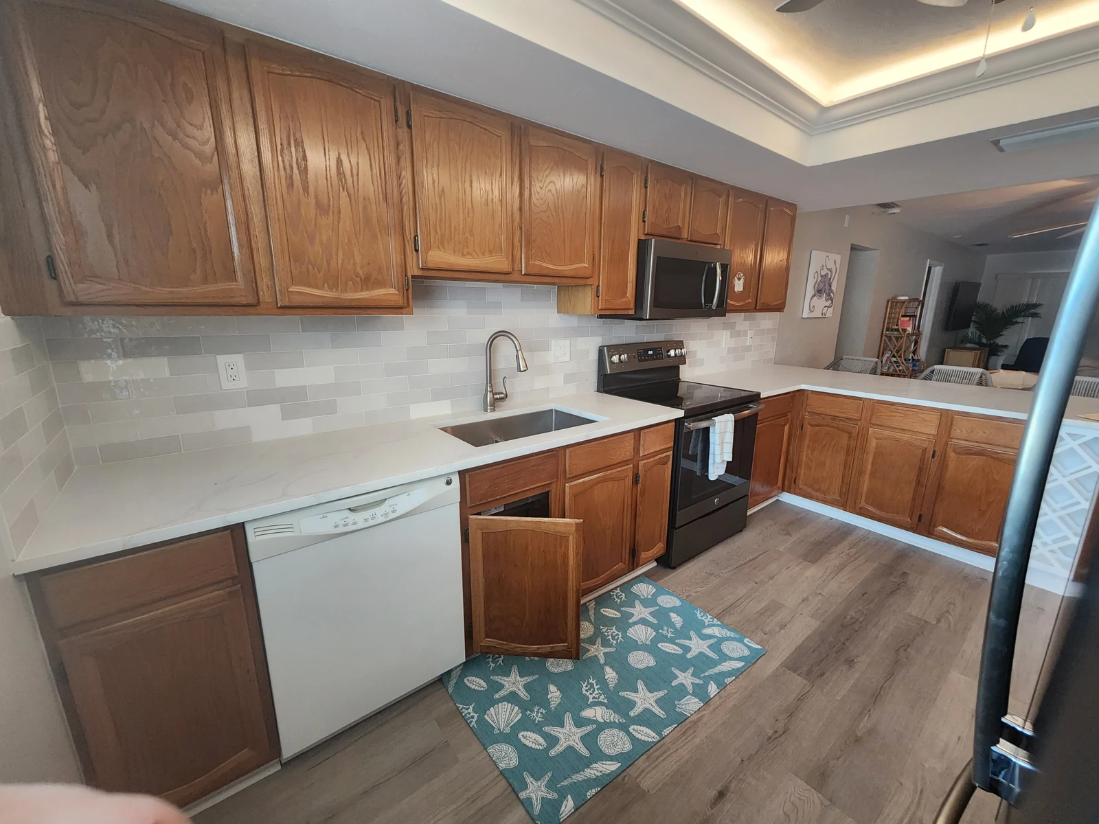 The same kitchen before refacing, seen along the cabinet run toward the peninsula