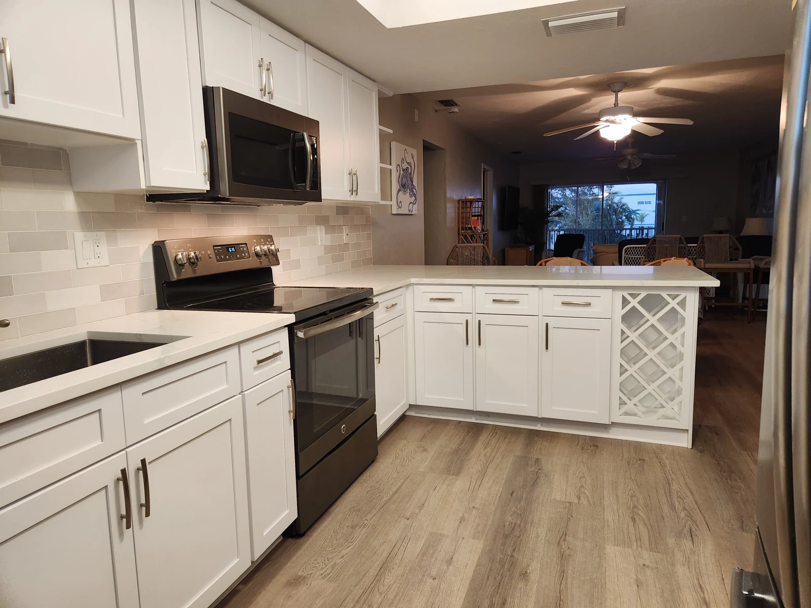 Refaced kitchen with white cabinetry, brushed pulls, a peninsula storage run and a wine-lattice end panel