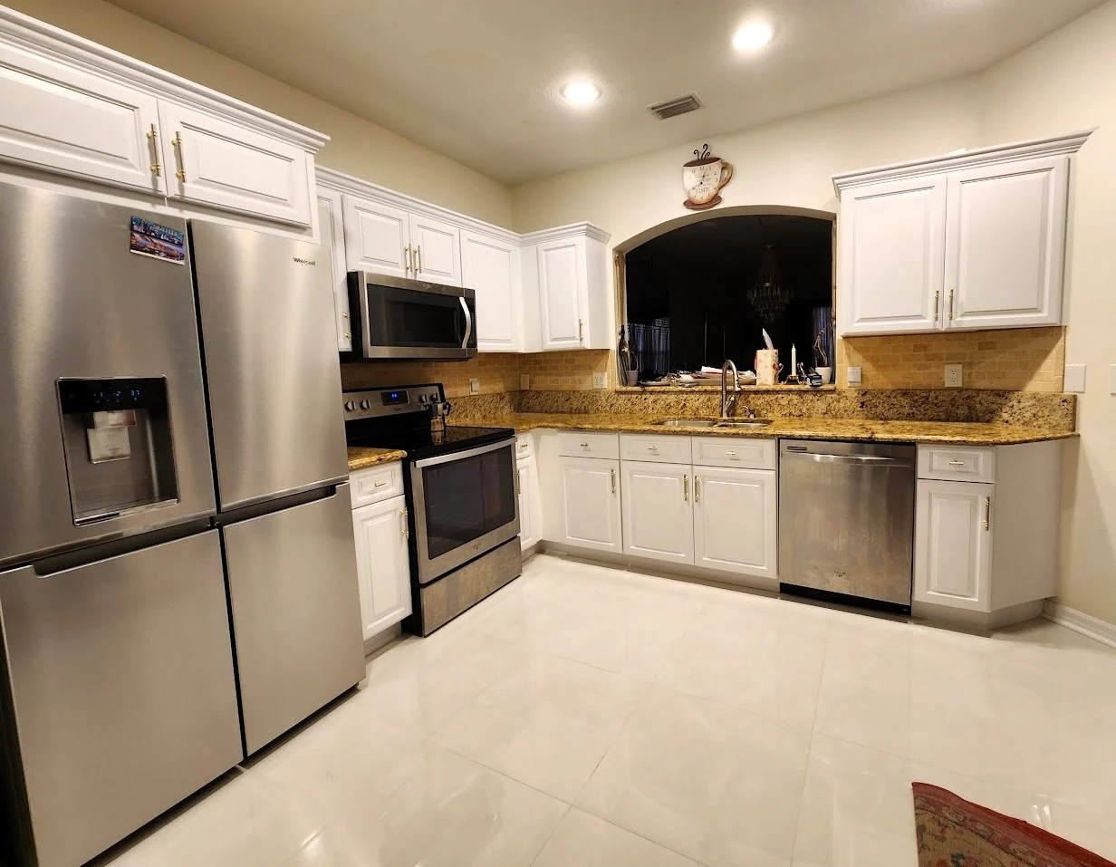 White cabinets around a kitchen sink with granite counters and stainless appliances